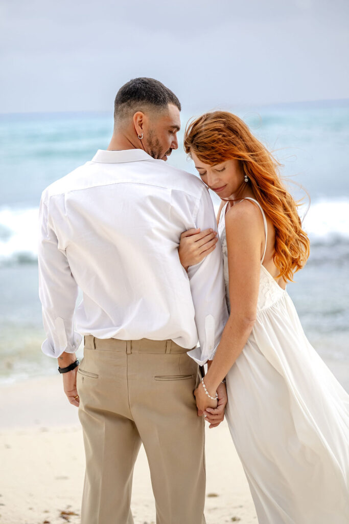 rothaarige Braut hält Arm von Bräutigam am Donauufer