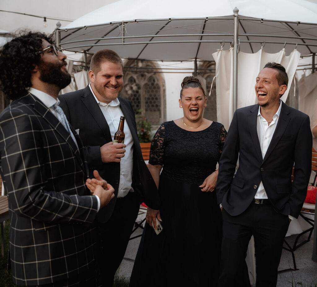 Hochzeitsgäste lachen nach der freien Trauung mit den Trauzeugen